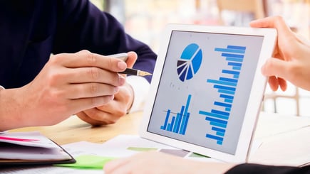 People reviewing charts and graphs displayed on a tablet during a business meeting