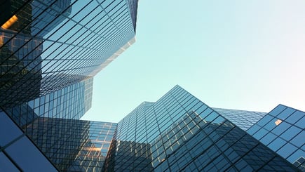 Upward view of modern glass office buildings reflecting the sky